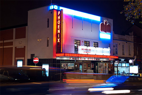an image of the outside of the pheonix theatre, taken at night the cinema is lit up by neon lighting