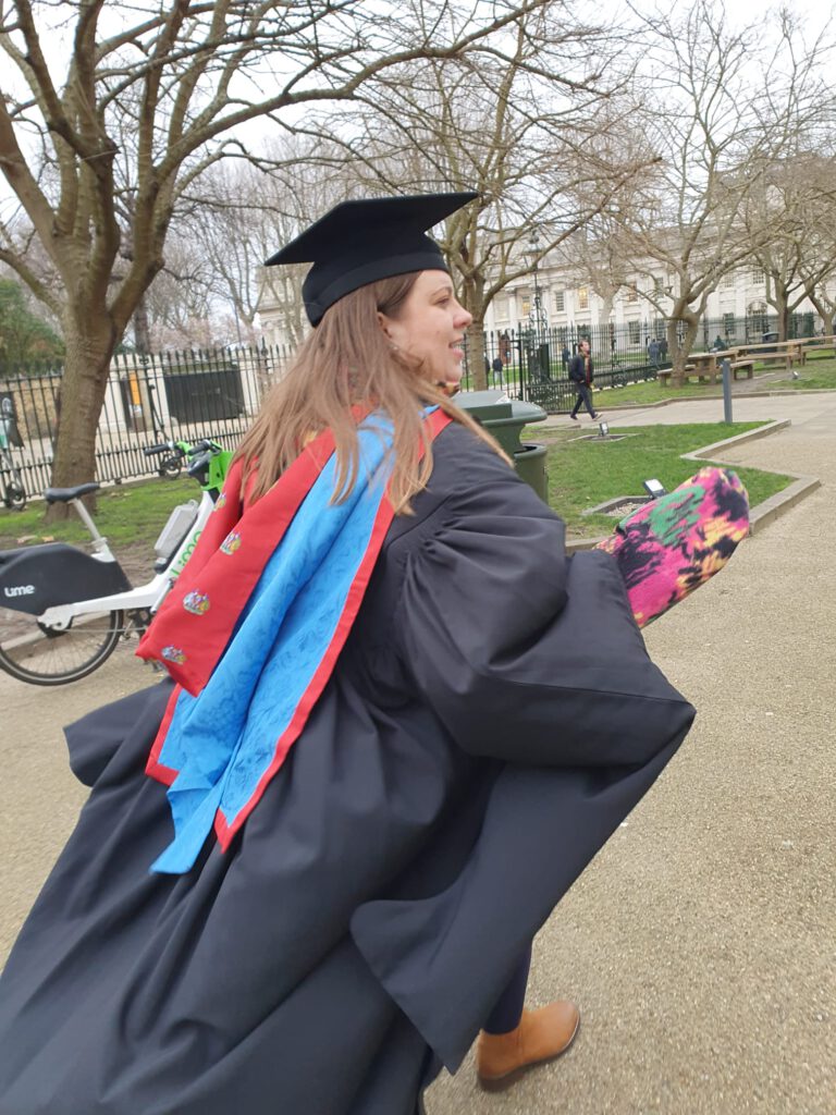 nikki wearing her graduation gowns, walking away creating a dramatic look of her gown flowing behind her
